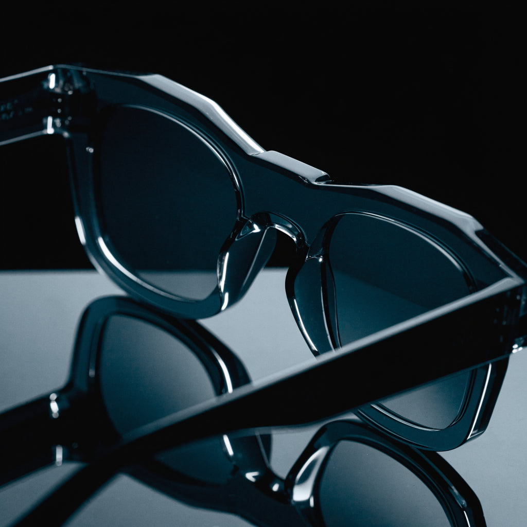 Bold thick acetate sunglasses under hard light on a black background, macro product photo