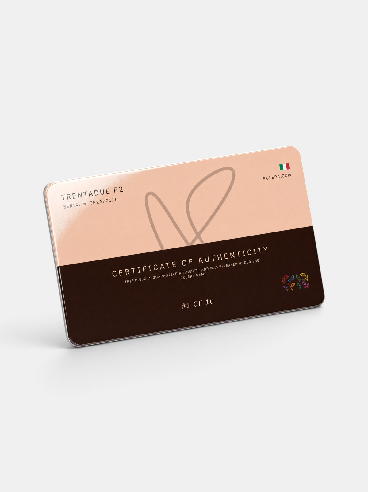 A rectangular Italian-style certificate of authenticity card with a split design: pale peach on the upper half and dark brown on the lower half, shown at an angle on a light gray background. Visible text includes 'TRENTADUE P2', 'CERTIFICATE OF AUTHENTICITY', and 'ITALIA' PULERA
